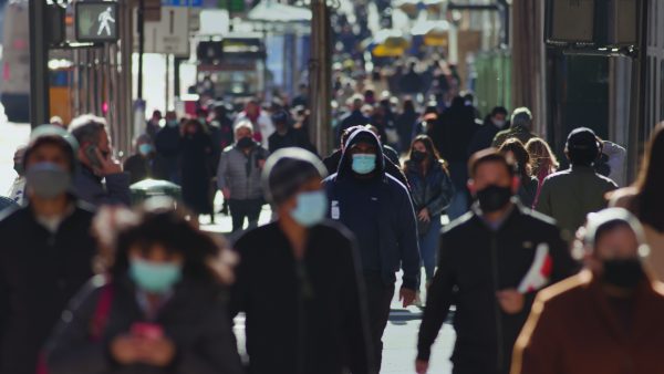 Crowd of people walking street wearing masks